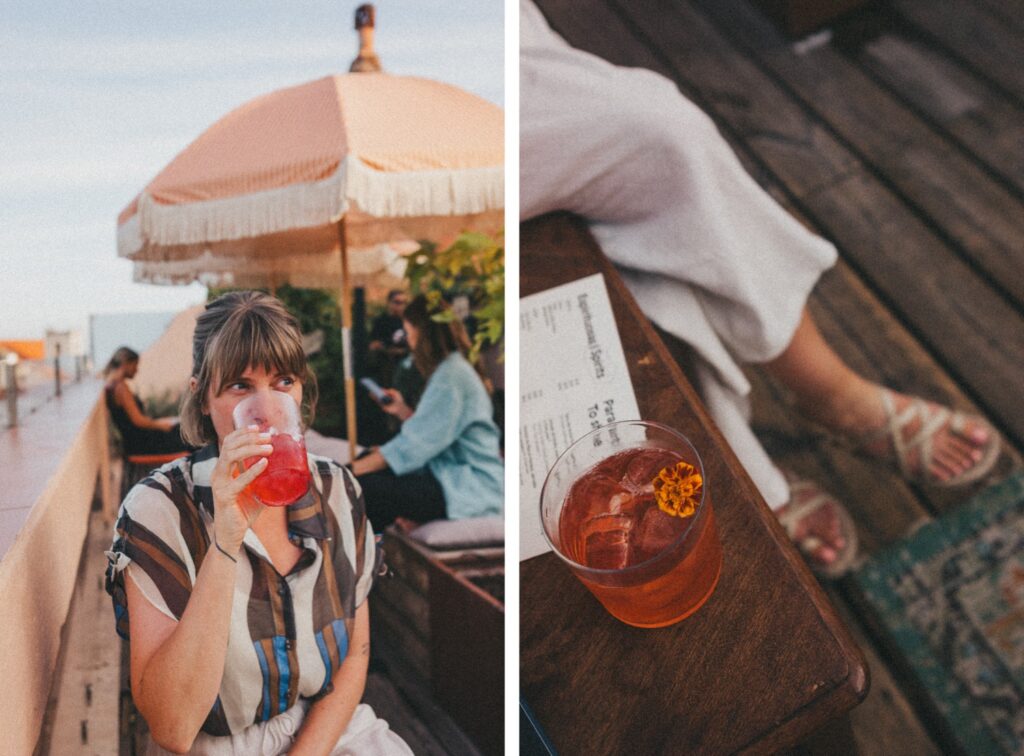 Eine Frau mit Pony und gestreiftem Hemd nippt auf einer Dachterrasse unter einem pfirsichfarbenen Sonnenschirm an einem roten Cocktail - eingefangen von einer Fotografin. Das zweite Foto zeigt eine Nahaufnahme des Cocktails, der Speisekarte und der Beine einer Person in Sandalen auf einem Holzfußboden.